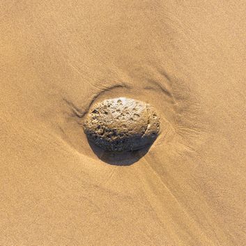 Volcanic rock resting in sand